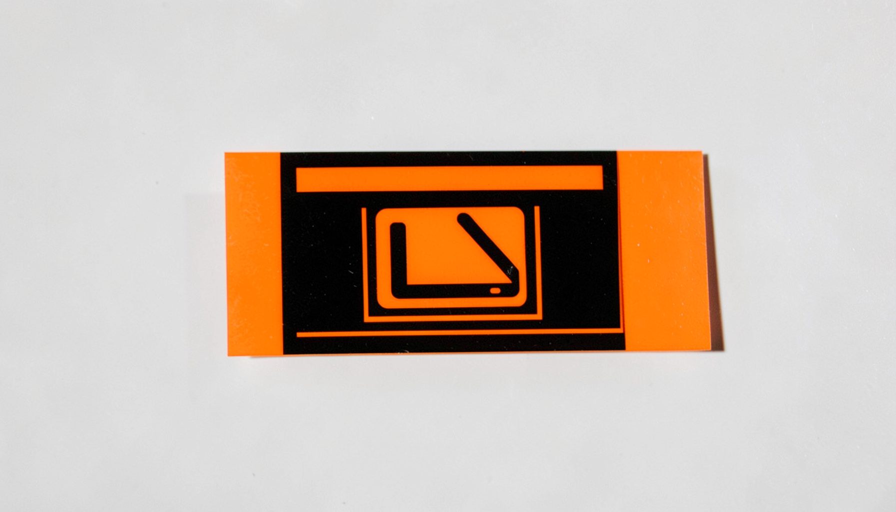 Vivid orange and black rectangular mark with a minimalist electronic-device silhouette